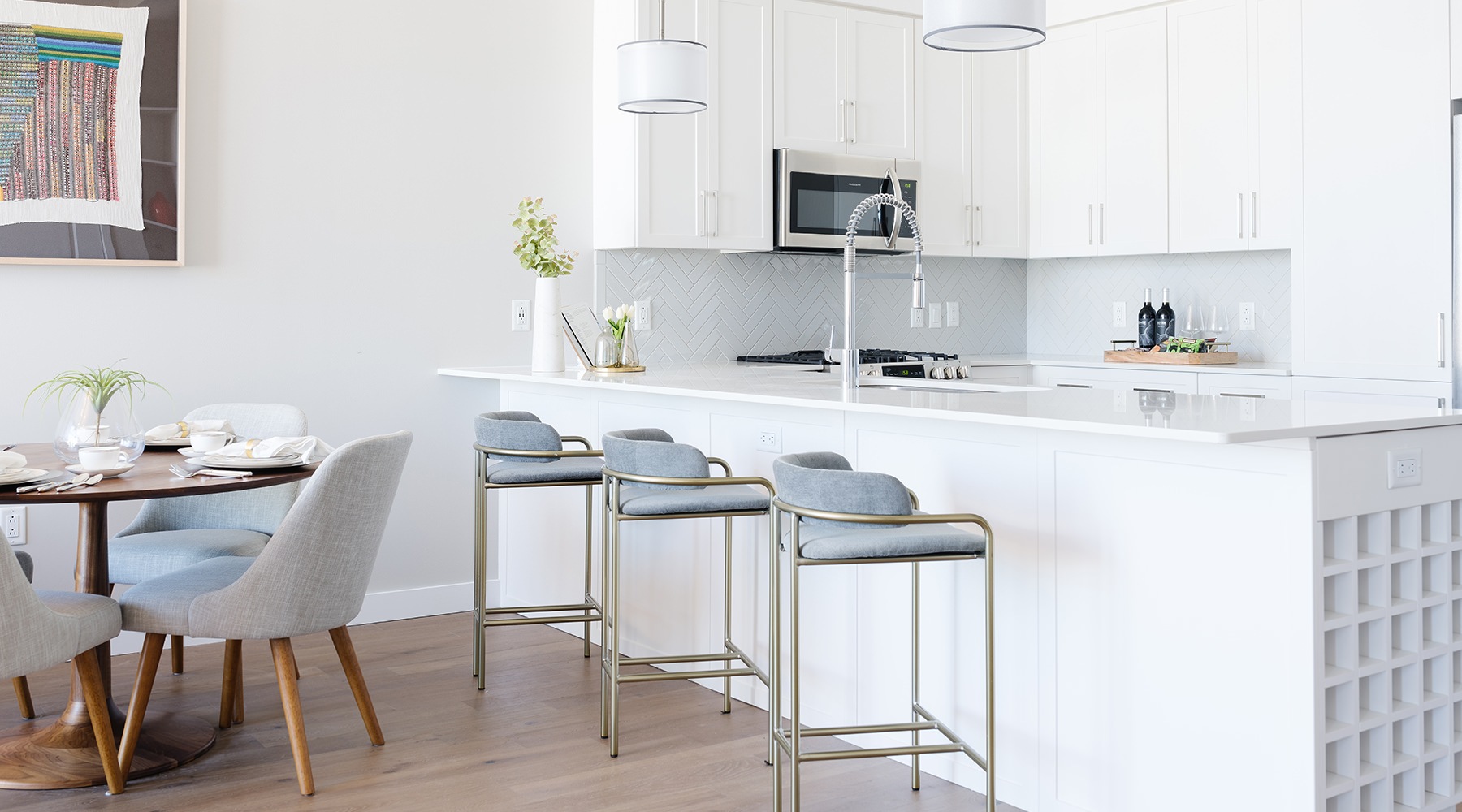 Spacious and well lit kitchen with wood floors and white accents