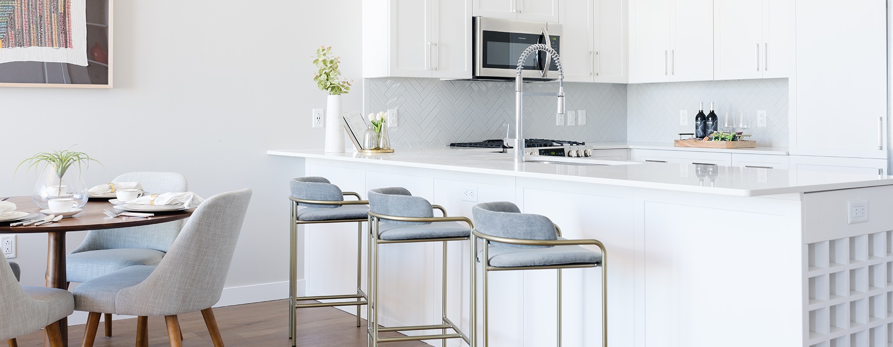 Spacious and well lit kitchen with wood floors and white accents