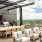One-Bedroom Apartments In The Gulch, Nashville, TN - 1200 Broadway - Outdoor Dining Area with BBQ Grill Station, Sink, TV, Dining Table And Chairs, Armchairs  Around Firepit, And City Skyline Views.