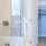 Large well lit bathroom with large mirror and white cabinets with a spacious walk in closet.